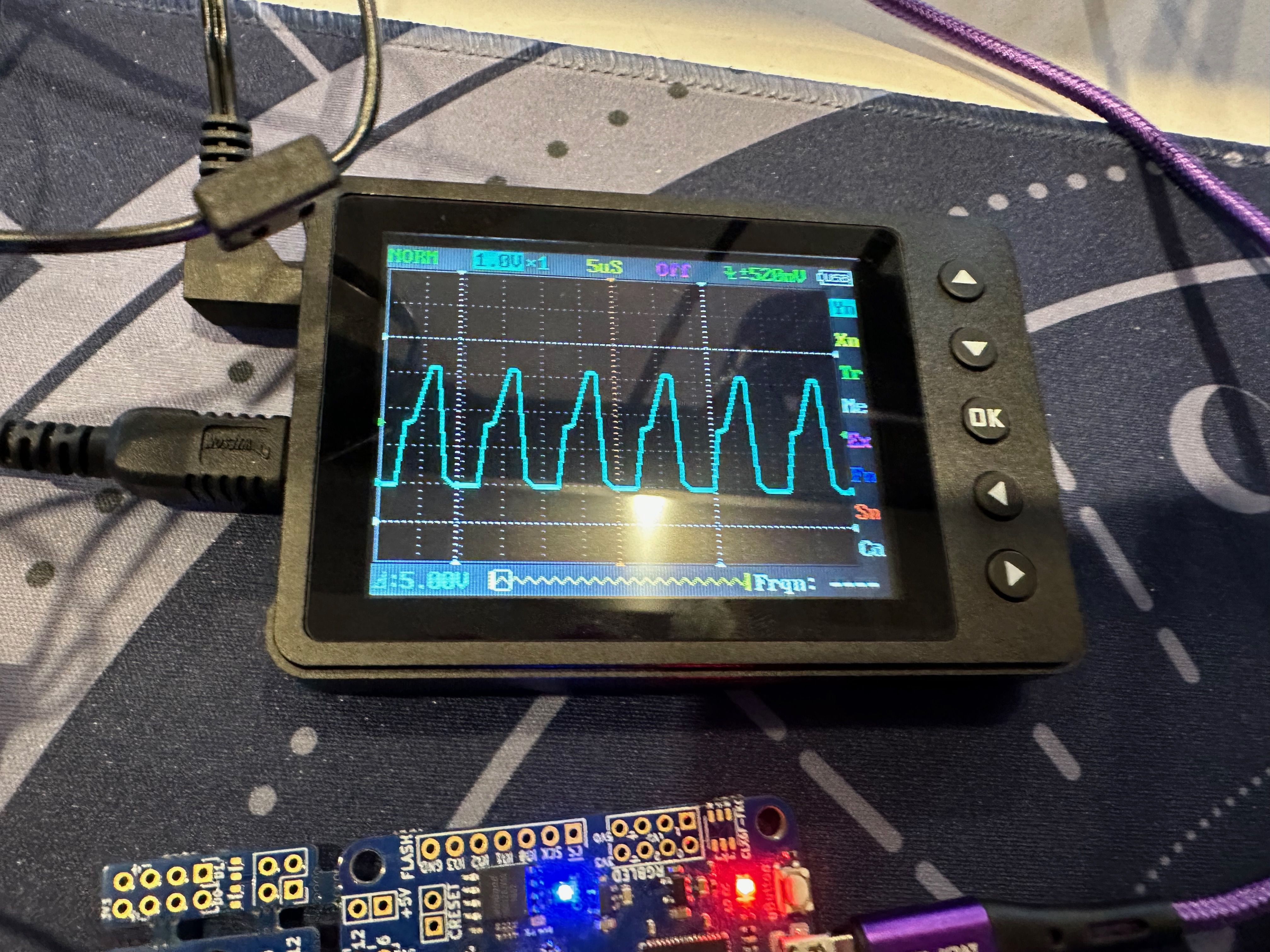 a few breadboards with various boards on them, an OLED, a few LEDs, an oscilloscope, way too many cables, a mess)
